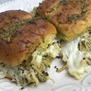 A white plate topped with two rolls of bread covered in cheese.
