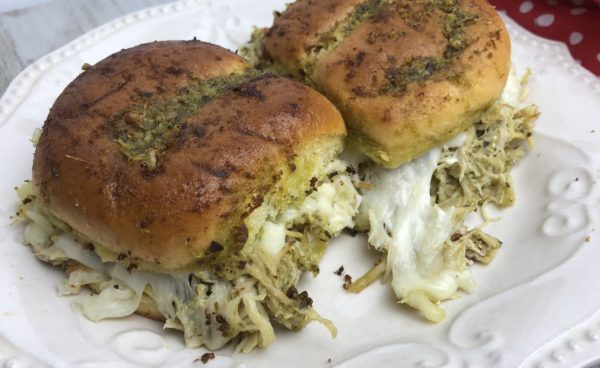 A white plate topped with two rolls of bread covered in cheese.