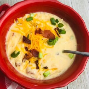 A bowl of soup with bacon, cheese and green onions.