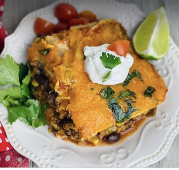 A white plate topped with food covered in cheese.