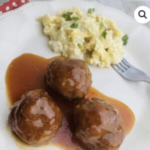 A plate of meatballs and mashed potatoes with gravy.