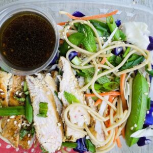 A plate of food with noodles, meat and vegetables.