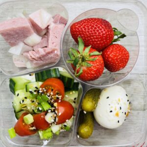 A tray of food with strawberries, cucumbers and other vegetables.