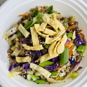 A bowl of food with noodles and vegetables.