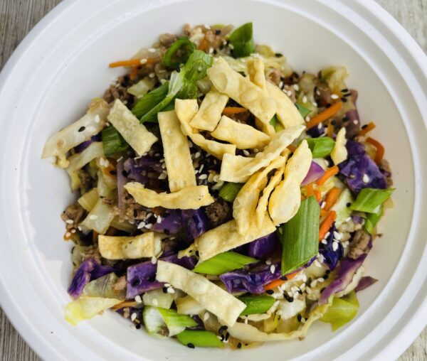 A bowl of food with noodles and vegetables.