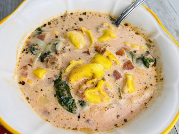 A bowl of soup with ham and cheese.