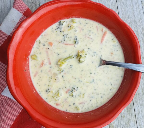 A bowl of soup with broccoli and carrots.