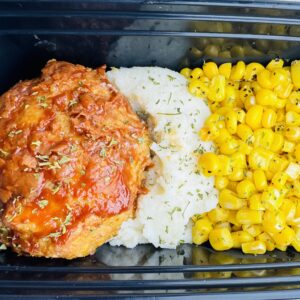 A meal of rice, corn and meat in a container.