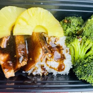 A meal of rice, pineapple and broccoli in a container.
