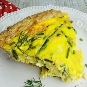 A slice of quiche on top of a white plate.