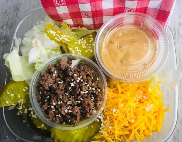 A bowl of food with cheese, meat and vegetables.